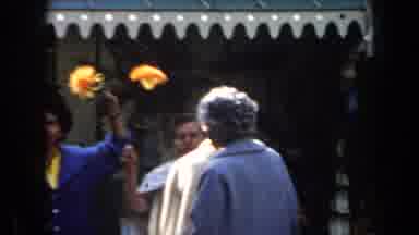California (1961): Women In Blue And Yellow Hold Flowers Up For A Line Of People