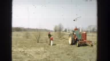 Wisconsin Dells Wisconsin-1954: A Man and Child Watch a Red Tractor in a Field