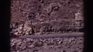Texas (1958): A Red And White Tractor Trailer Driving On Road Along A Rocky