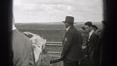 Washington (1938): Man Wearing Grey Jacket Sit On Stone Railing Of House On A