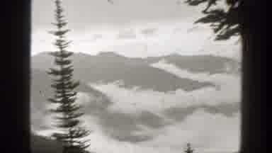 California (1938): Clouds And Fog Fill Ravines Of Forested Mountains Under An