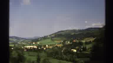 Norway (1976): Passing View Of Green Mountains Blue Sky And White Buildings