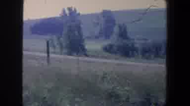 Iowa (1959): View Of Green Trees And Brown Buildings On A Sunny Day