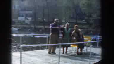 Novi Michigan (1961): Three People On Wooden Pier Over Body Of Water Holding Up A