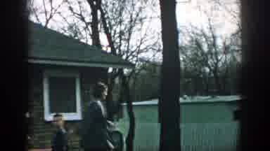 Wisconsin (1957): Woman Walking Around In Yard Throwing Something While Boy