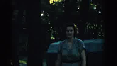 Wisconsin (1957): A Woman Walks In A Yard With Trees And Then Stands Next To A