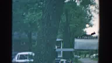 Wisconsin (1957): Woman Wearing Blue Dress Walks Toward Tan Stone Building On A