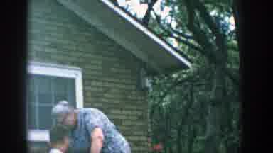 Wisconsin (1957): Elder Woman Cleaning A Garden Pot In Front Of Boy On His Bike
