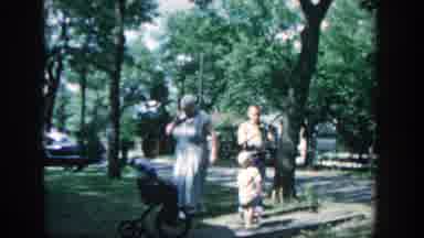 Wisconsin (1957): Family Watches Young Boy Pedal Tricycle Over To Toddler While