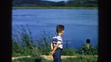 Wisconsin (1957): Small Boy Strolls Contently By The Lake Turning To Flash The