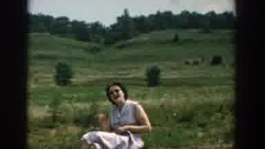 Wisconsin (1957): A Woman Sitting In A Grassy Field Smokes And Smiles Followed By
