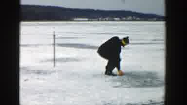 Wisconsin (1957): People Putting Something On The Frozen Ground With Mountains And