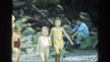 Connecticut (1947): Three Child Walk On Sand While Their Family Sits Nearby