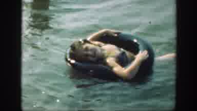 Connecticut (1947): Small Child Relaxes In Black Inner tube In Lake Water On A