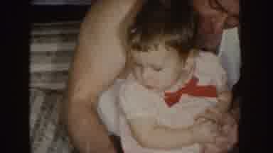 Nebraska (1955): Man Wearing White T-Shirt Holds Baby Wearing Red And White Shirt