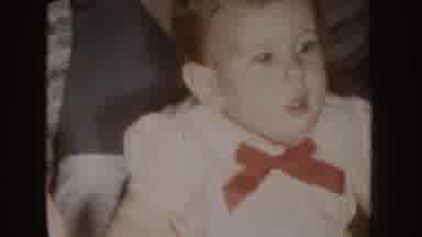 Nebraska (1955): A Baby Dressed In White With A Red Bow Playing On The Floor Next