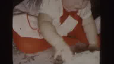 Nebraska (1955): Baby Wearing Red And White Shirt Sits On Floor Eating Cake