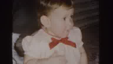 Nebraska (1955): Baby Girl In A White Dress With Red Ribbon Eating A Snack In
