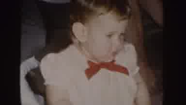 Nebraska (1955): Baby With Red Bowie Shaking Arm In The Air While Sitting On A