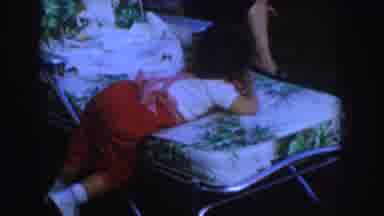 Nebraska (1955): Toddler Wearing Red Overalls Sits In Small White Rocking Chair On