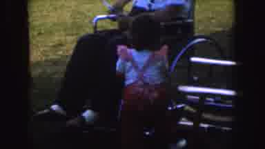 Nebraska (1955): People Sitting In A Grassy Area And Child Walking Towards The Man