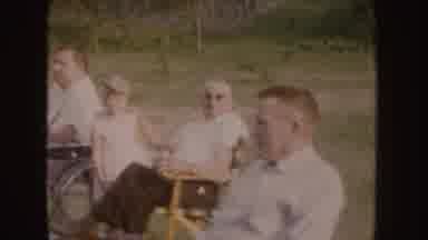 Nebraska (1955): People Sitting Eating Food At Picnic On A Clear Day