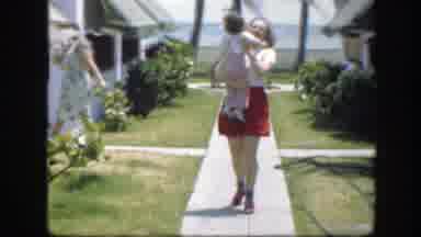 Florida (1945): Woman Carrying A Child Is Walking Down The Sidewalk Near The Beach