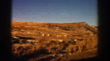 Aspen Colorado (1961): Passing View Of Black Car On Highway On A Sunny Day
