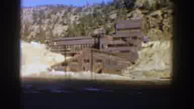 Aspen Colorado (1961): A Vehicle Drives By An Abandoned Mine Sitting At The Bottom
