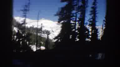 Aspen Colorado (1961): Driving Down A Hillside Road Snow capped Mountains Visible