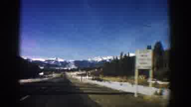 Aspen Colorado (1961): Driving On A Long Road Towards Mountains Where Snow Lightly