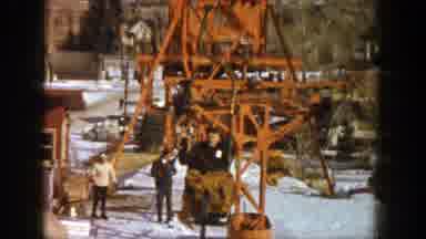 Aspen Colorado (1961): Person Wearing Brown Coat Rides Ski Lift On A Clear Sunny