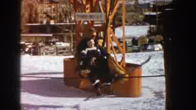 Aspen Colorado (1961): Man With A Child On His Lap Ride A Ski Lift At A Resort As