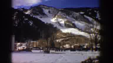 Aspen Colorado (1961): View Of Snow Covered Mountains And Brown Buildings On A