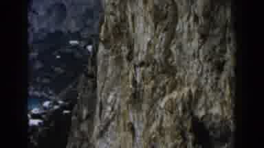Italy (1960): The Rock Face Of A Mountain Rises To A Summit Above A Sea Cove