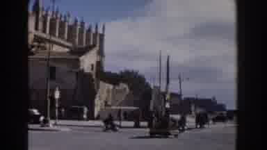 Italy (1960): View Of Tan Building And Light Traffic On A Sunny Day