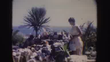 California (1962): Woman Wearing Yellow Dress Looks At Blooming Red And White