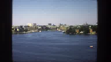 Stockholm Sweden (1975): A Boat Sales Down A Body Of Water Surrounded By Buildings