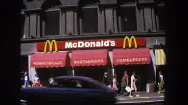 STOCKHOLM SWEDEN-1975: Camera Focuses On A McDonald's Restaurant Store Front While Pedestrians Walk By