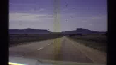 Arizona (1969): View From Windshield Traveling Down An Open Road Near Mountains