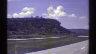 Arizona (1969): A Vehicle Drives Down A Highway Through A High Desert Area With