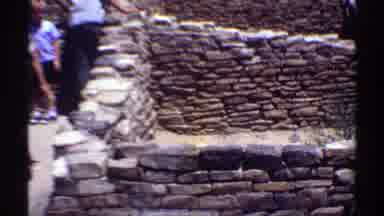 Arizona (1969): Several People Next To Rock Brick Constructions In A Place With