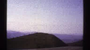 Arizona (1969): A Vehicle Passes Through Rolling Hills And Mountains During