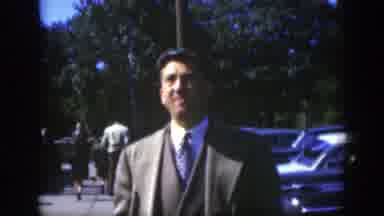 MONTREAL CANADA-1950: Man In Suit Stands In Parking Lot, Woman Reads Newspaper