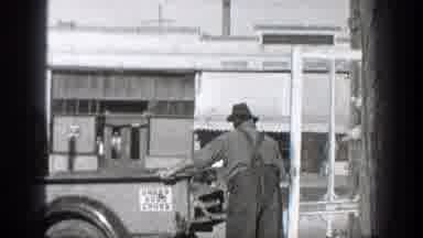 California (1936): A Man Wearing Hat Is Entering A Vehicle And Another One Waving