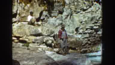 California (1936): Man Wearing Red Shirt Looks At Rushing River On A Sunny Day