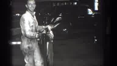 California (1936): Man Wearing White Jumpsuit Walks To Black Car Holding Grey