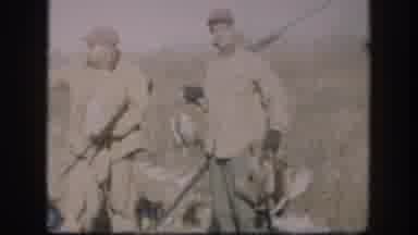 Kansas (1958): Man Wearing Red Hat Walks In Field Carrying Rifle On A Sunny Day