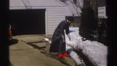 Michigan (1969): Woman Standing In Front Of House Picking Up Snow From The Ground