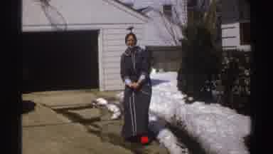 Michigan (1969): Woman Dressed In Robe By Two-Car Garage Throws Snowball And